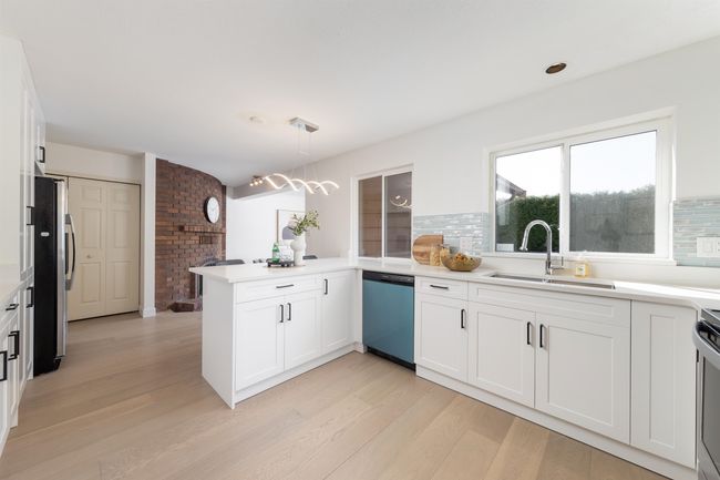 Kitchen featuring light wood-type flooring, a sink, a peninsula, and dishwasher | Image 11