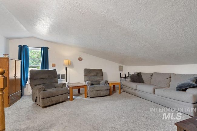 Carpeted living room featuring a textured ceiling and lofted ceiling | Image 23