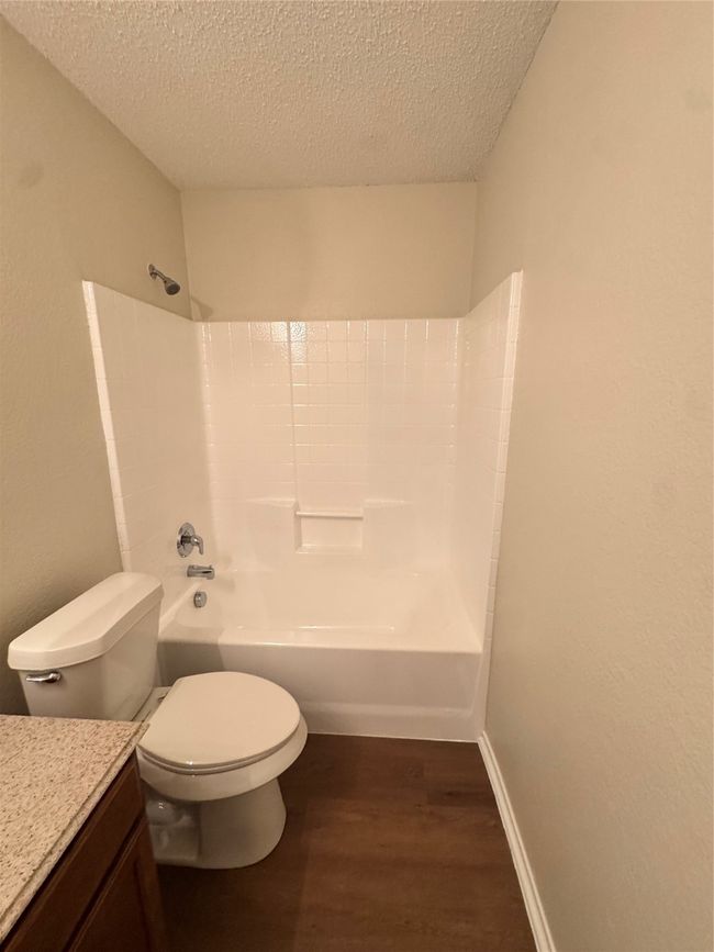 Full bath featuring wood finished floors, vanity, a textured ceiling, toilet, and shower / tub combination | Image 15