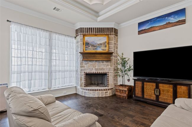 Living room featuring wood finished floors, ornamental molding, a fireplace, and a raised ceiling | Image 6