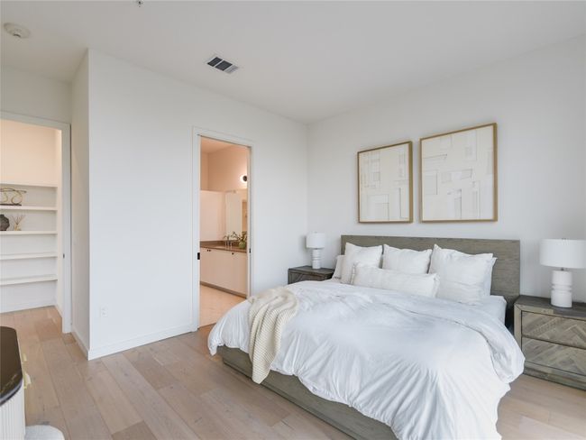Bedroom featuring baseboards, visible vents, ensuite bathroom, a walk in closet, and light wood-type flooring | Image 14