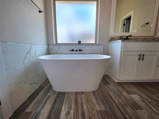 Full bath with vanity, a soaking tub, tile walls, wood finished floors, and a wainscoted wall | Image 25