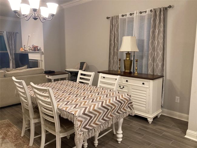 Dining area with ornamental molding, wood finish floors, a notable chandelier, and baseboards | Image 8