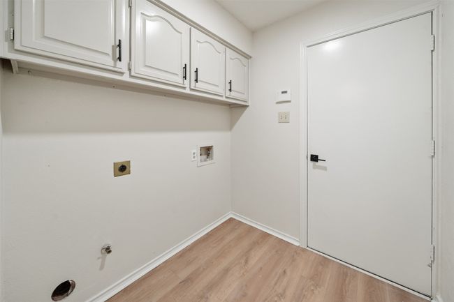 Laundry room with cabinet space, light wood finished floors, hookup for a washing machine, baseboards, and hookup for an electric dryer | Image 20