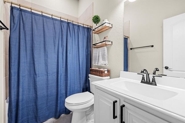 Full bathroom with vanity, shower / bath combination with curtain, and a textured wall | Image 15