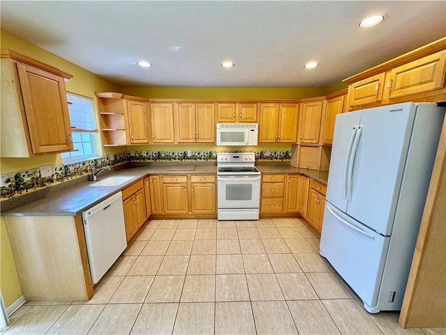 Kitchen with upgraded maple cabinets and beautiful neutral ceramic tile flooring. | Image 7