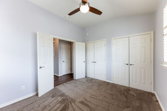 Unfurnished bedroom with carpet floors, two closets, lofted ceiling, and ceiling fan | Image 20