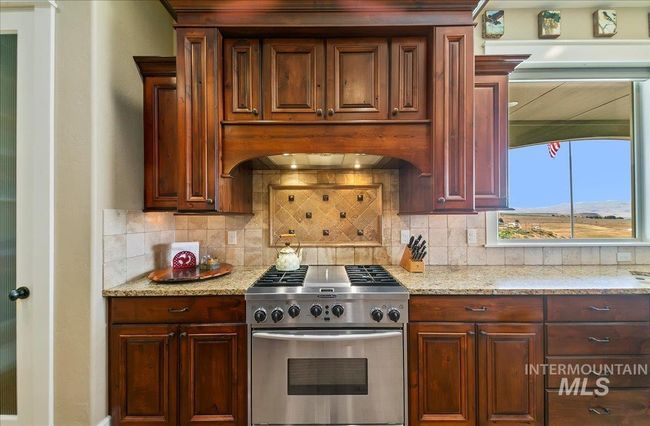 Kitchen featuring high end range, custom range hood, backsplash, and light stone counters | Image 12