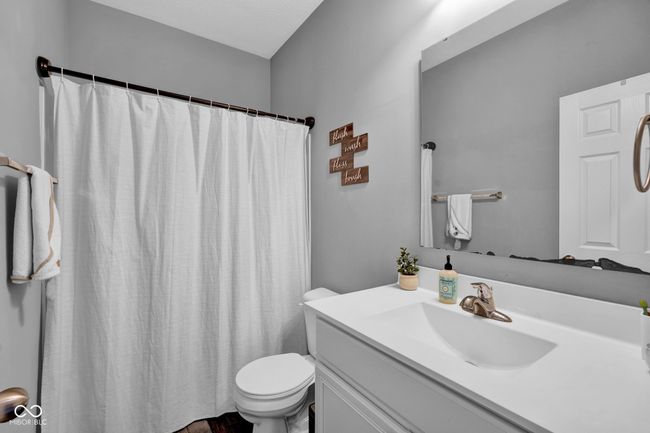 bathroom featuring toilet, curtained shower, and vanity | Image 8
