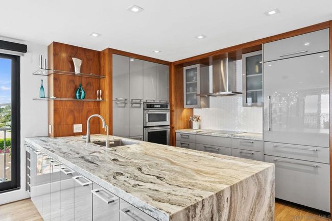 Beautiful electric kitchen equipped with Thermador appliances, induction cooktop, Miele dishwasher and waterfall granite countertop. | Image 11