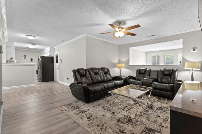 Living area featuring a ceiling fan, a textured ceiling, visible vents, crown molding, and light wood-type flooring | Image 5