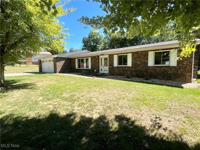 Ranch-style house with a front yard and a garage | Image 1