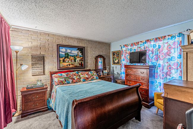 Bedroom with a textured ceiling and brick wall | Image 10