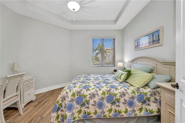 Bedroom with a tray ceiling, wood finished floors, and ceiling fan | Image 25
