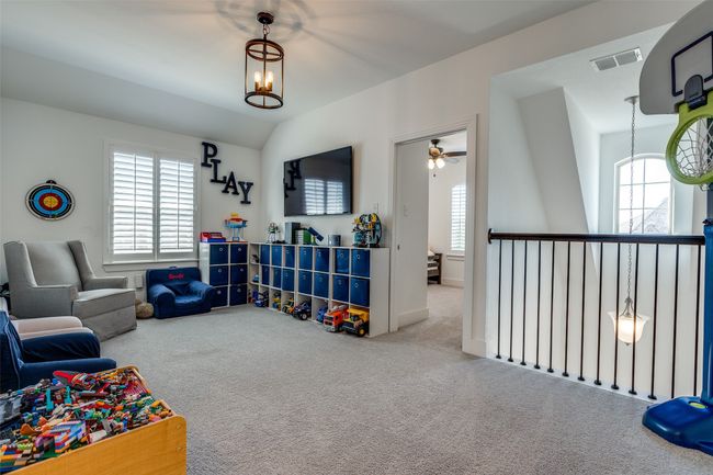 Recreation room featuring visible vents, carpet flooring, lofted ceiling, and ceiling fan with notable chandelier | Image 10