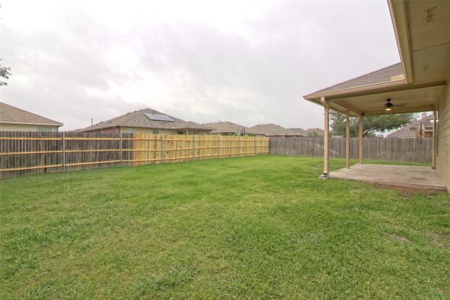 Fenced backyard with a patio area and a ceiling fan | Image 29