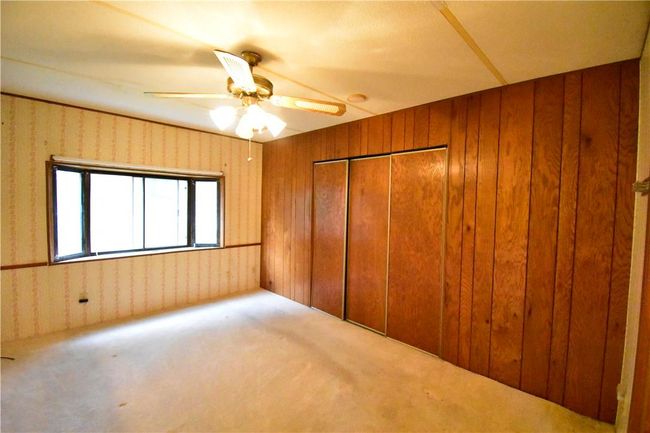 Unfurnished bedroom featuring a closet, wood walls, ceiling fan, and carpet flooring | Image 18