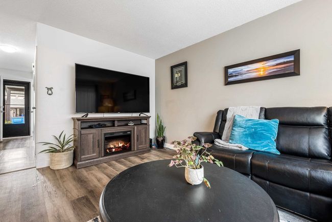 Living area with baseboards, a lit fireplace, wood finished floors, and a textured ceiling | Image 12