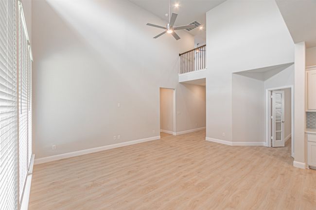 Unfurnished living room with light wood-style flooring, ceiling fan, and a high ceiling | Image 17