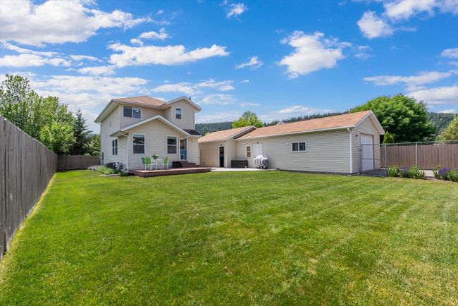 Back of property featuring a fully fenced backyard with landscaping and a deck | Image 37