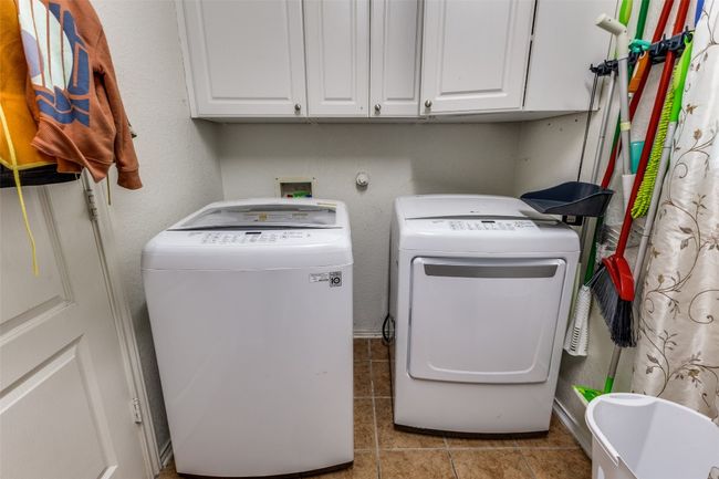 Washroom featuring independent washer and dryer, cabinet space, and tile patterned floors | Image 22