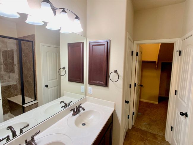 Bathroom featuring a shower stall, double vanity, tile patterned floors, and a walk in closet | Image 5