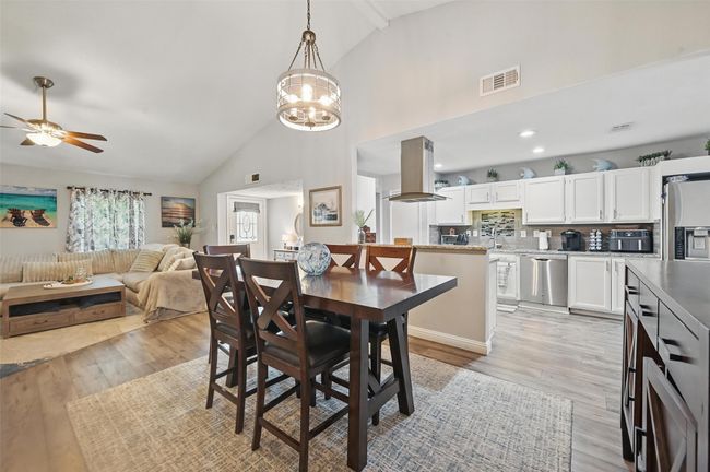 Dining space with high vaulted ceiling, a ceiling fan, light wood-style floors, a chandelier, and beam ceiling | Image 9