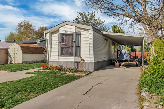 View of front facade featuring a front lawn, driveway, an attached carport, an outbuilding, and a storage unit | Image 16