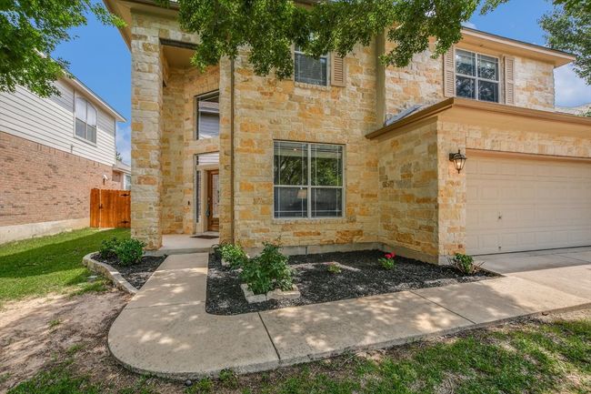 View of front facade with stone siding, an attached garage, and fence | Image 29