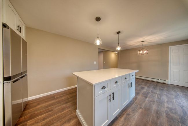 Kitchen featuring baseboard heating, white cabinetry, baseboards, dark wood-style flooring, and freestanding refrigerator | Image 12