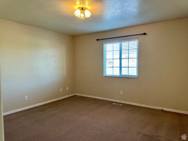 Primary room with carpet floors and a large window sending in natural light | Image 8