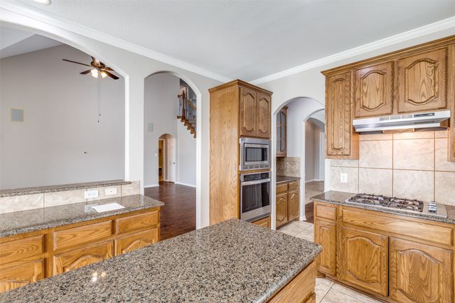 Kitchen with stainless steel appliances, under cabinet range hood, arched walkways, and crown molding | Image 9