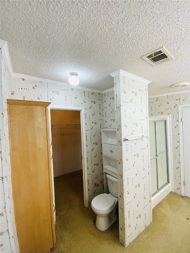 Bathroom featuring wallpapered walls, visible vents, a textured ceiling, and ornamental molding | Image 22