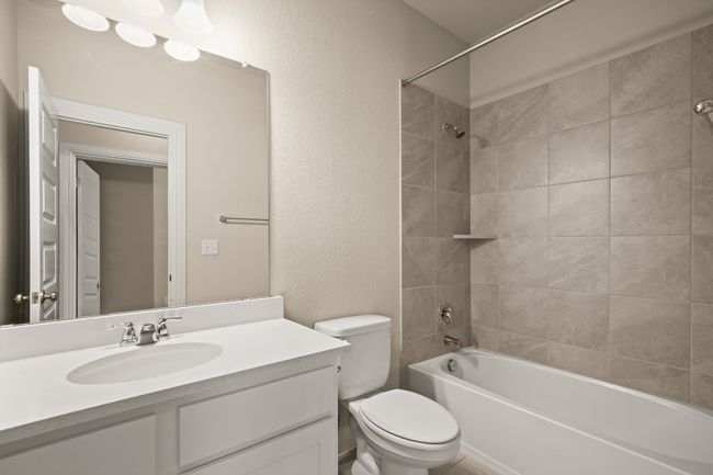 Bathroom with toilet, bathing tub / shower combination, vanity, and a textured wall | Image 24