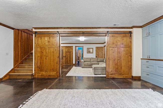 Unfurnished living room with ornamental molding, a barn door, and a textured ceiling | Image 35