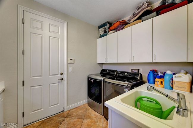 Laundry area with cabinet space, washing machine and clothes dryer, and light tile patterned floors | Image 41