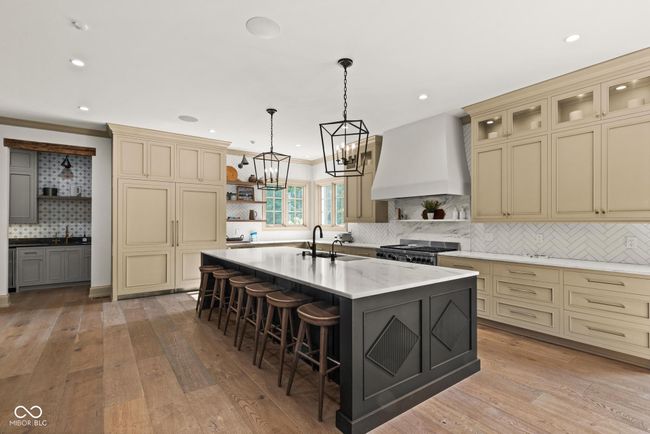 kitchen featuring open shelves, custom exhaust hood, cream cabinets, a sink, and decorative backsplash | Image 12