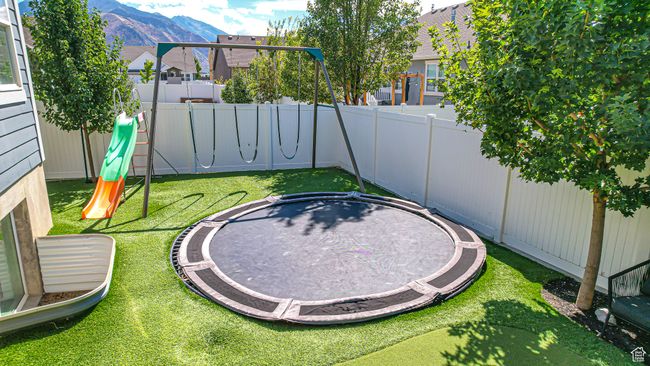 View of yard with a fenced backyard, a playground, a mountain view, and a trampoline | Image 47