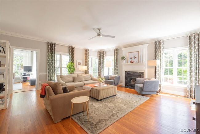 Living room with ornamental molding, light wood-type flooring, a ceiling fan, and a high end fireplace | Image 12