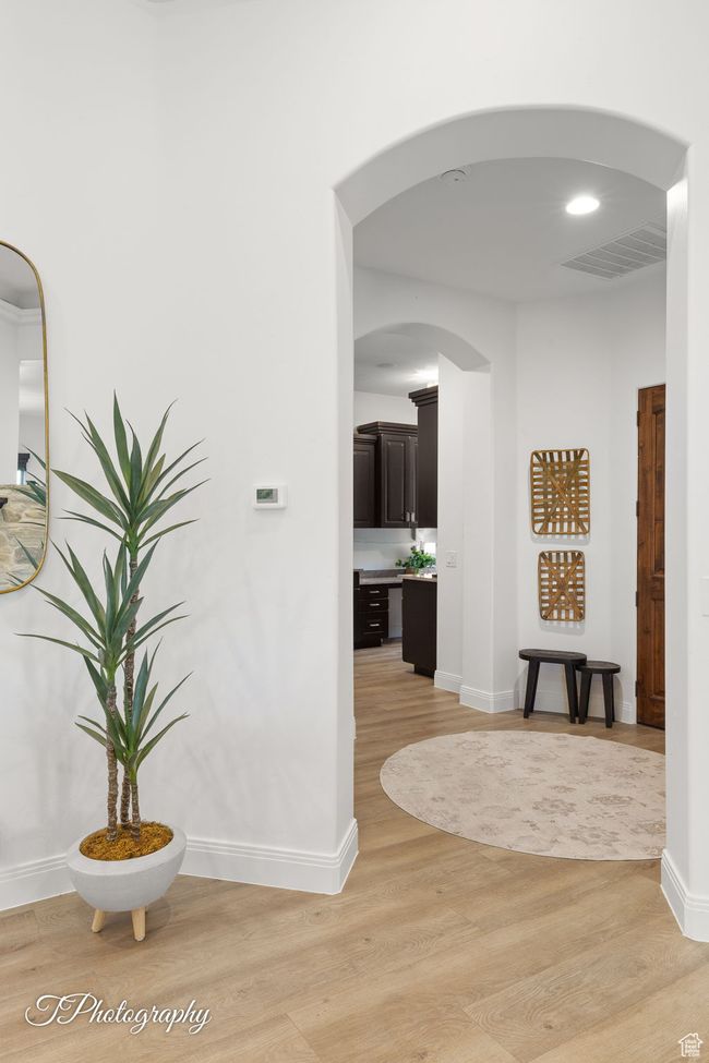 Hallway featuring light wood-type flooring, baseboards, and arched walkways | Image 69