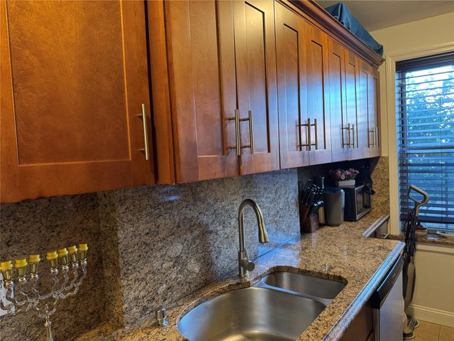 Kitchen featuring decorative backsplash, light stone countertops, tile patterned floors, stainless steel dishwasher, and sink | Image 11