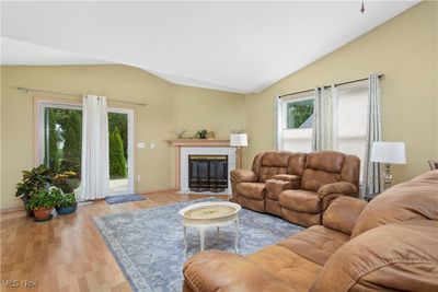 Living room featuring a tiled fireplace, vaulted ceiling, and light hardwood / wood-style floors | Image 2