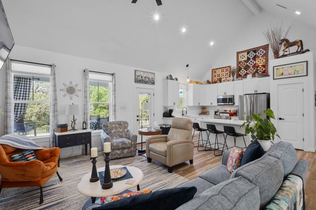 Living area with light wood-style floors, high vaulted ceiling, ceiling fan, and beam ceiling | Image 11
