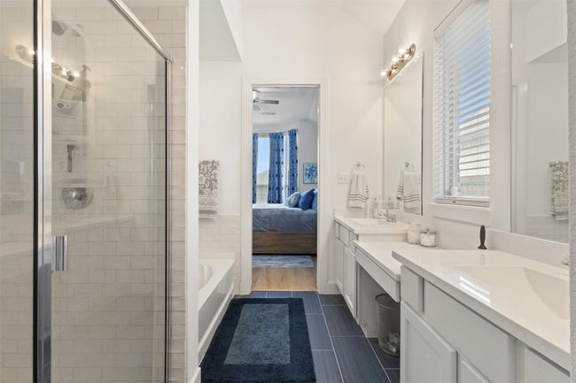 Ensuite bathroom with double vanity, a stall shower, healthy amount of natural light, and a bath | Image 9
