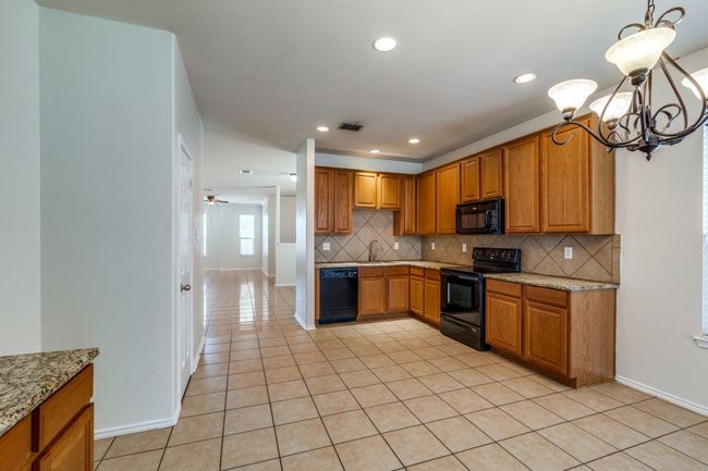 Kitchen with tasteful backsplash, light tile patterned flooring, and black appliances | Image 8