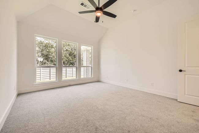 Empty room with carpet floors, healthy amount of natural light, ceiling fan, lofted ceiling, and baseboards | Image 18