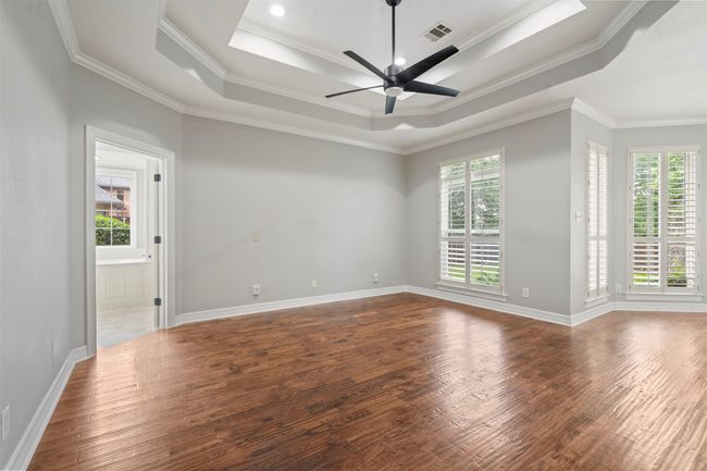 Empty room featuring wood finished floors, a tray ceiling, crown molding, baseboards, and ceiling fan | Image 19