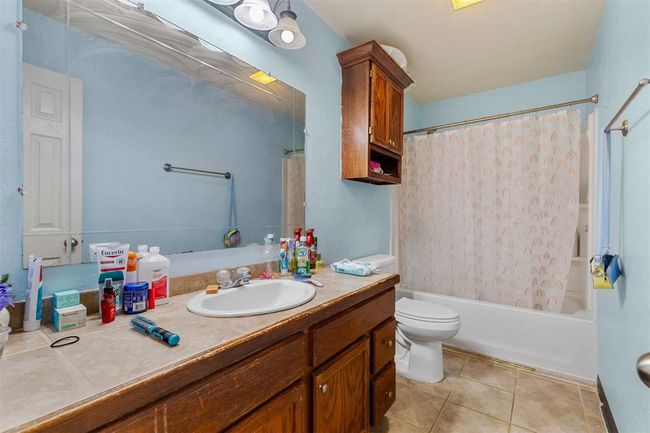 Full bathroom with vanity, shower / tub combo with curtain, tile patterned floors, and toilet | Image 11