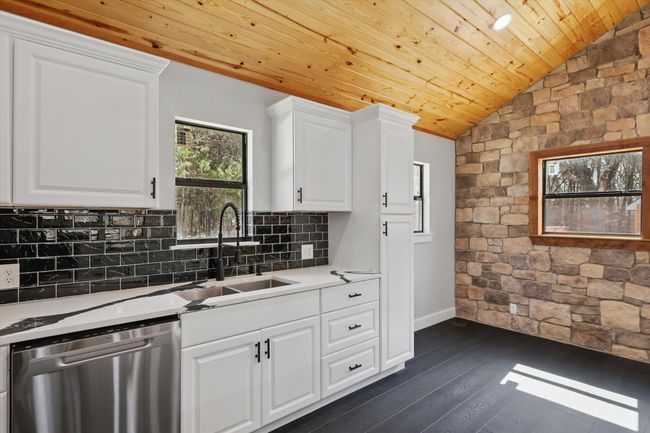 Kitchen featuring a sink, wood ceiling, vaulted ceiling, stainless steel dishwasher, and backsplash | Image 20