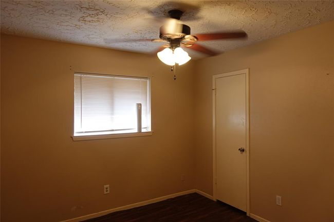 Inviting middle bedroom with cozy lighting and a ceiling fan for comfort. | Image 13